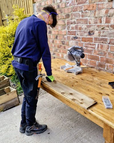 Frankie working in safety glasses, mask, gloves and a tool belt