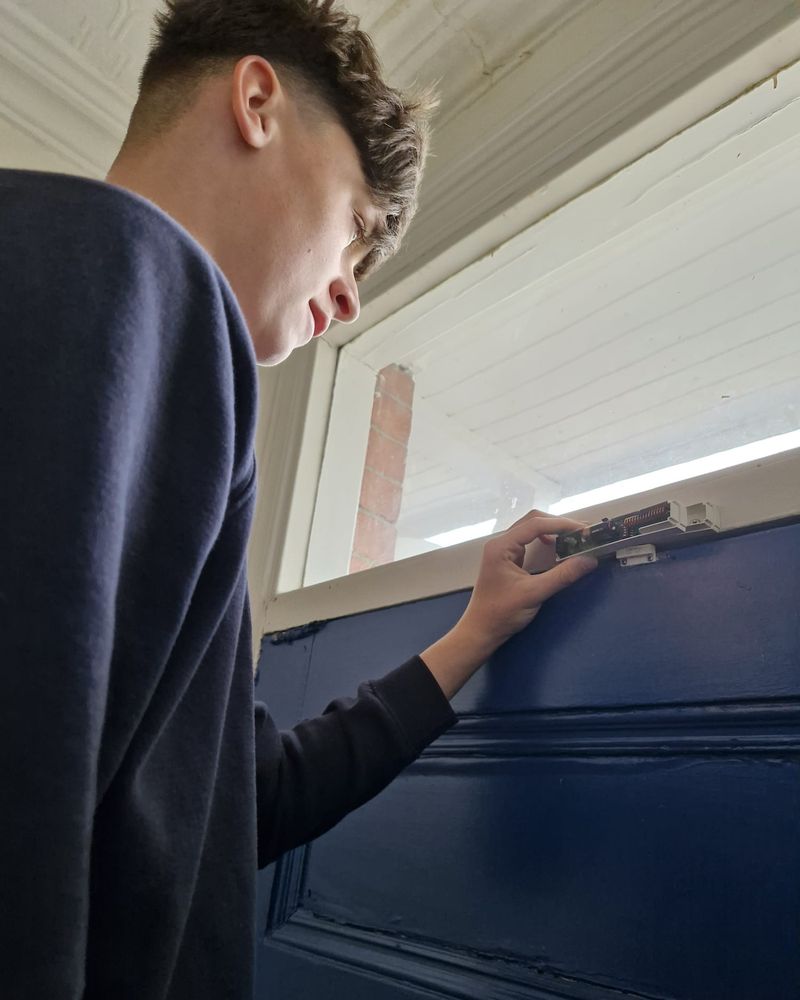 Frankie fitting a sensor at the top of a front door